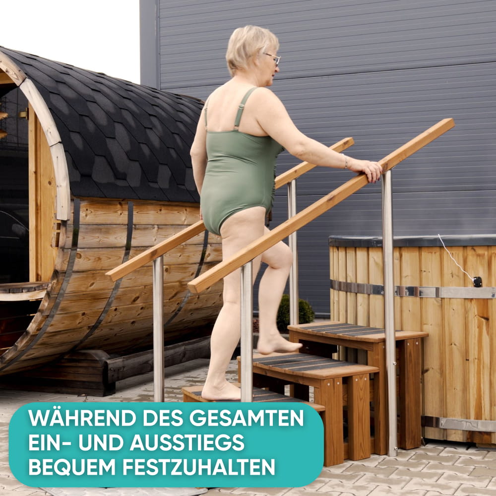Ältere Frau steigt über eine Hot-Tub-Treppe in einen Fass-Hot-Tub und hält sich dabei am seitlichen Handlauf fest