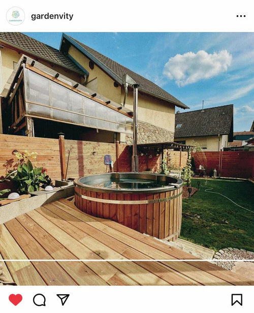 Round wooden hot tub integrated into a backyard with modern wooden decking and nearby home structures, illustrating customized outdoor installation.
