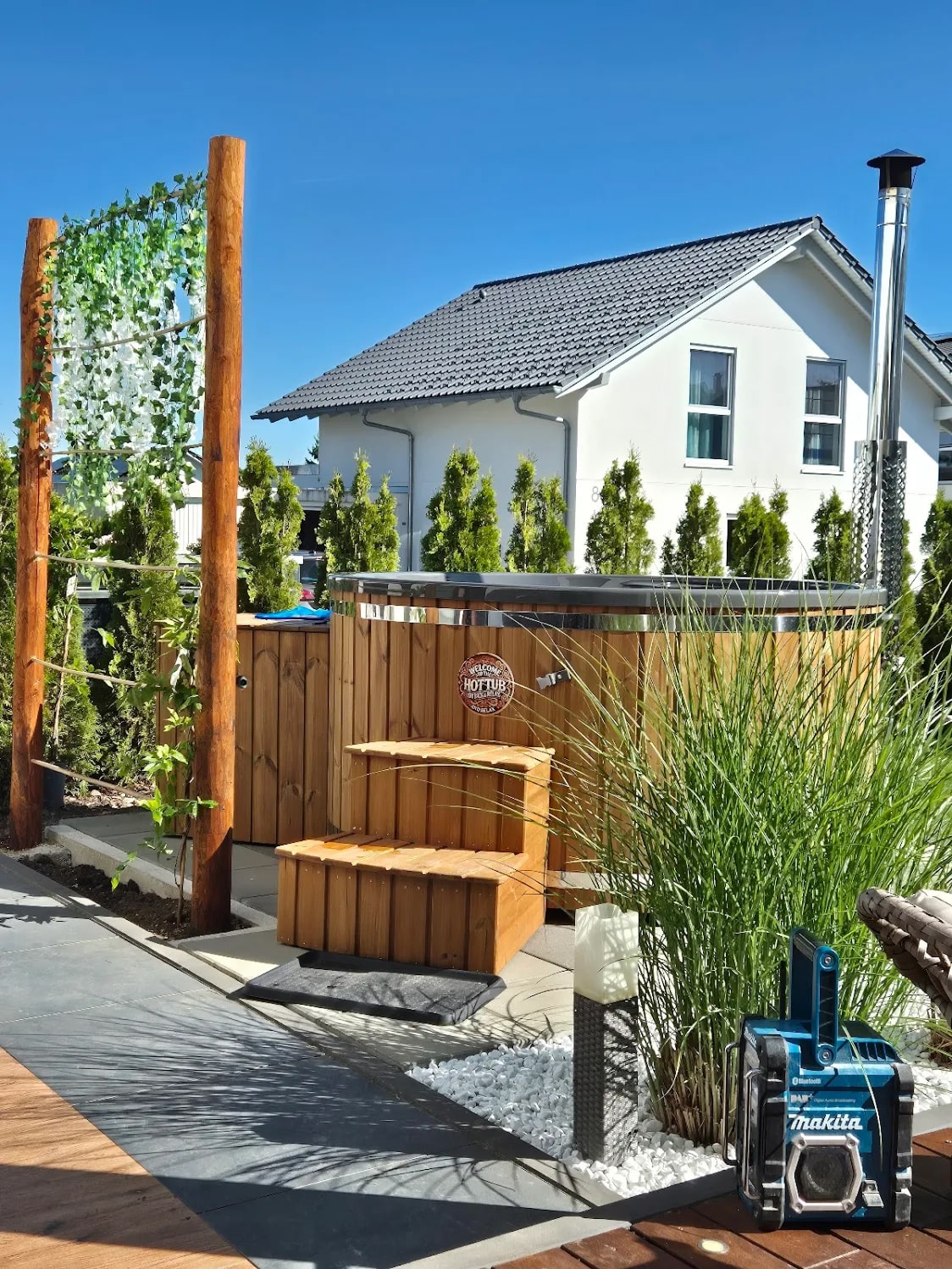 Gardenvity wood fired hot tub installed in a private garden with wooden steps and greenery