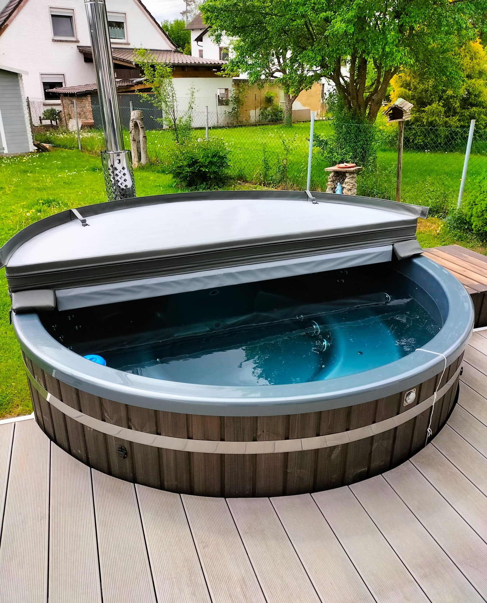 Compact Gardenvity wood fired hot tub with insulated cover in a small green backyard