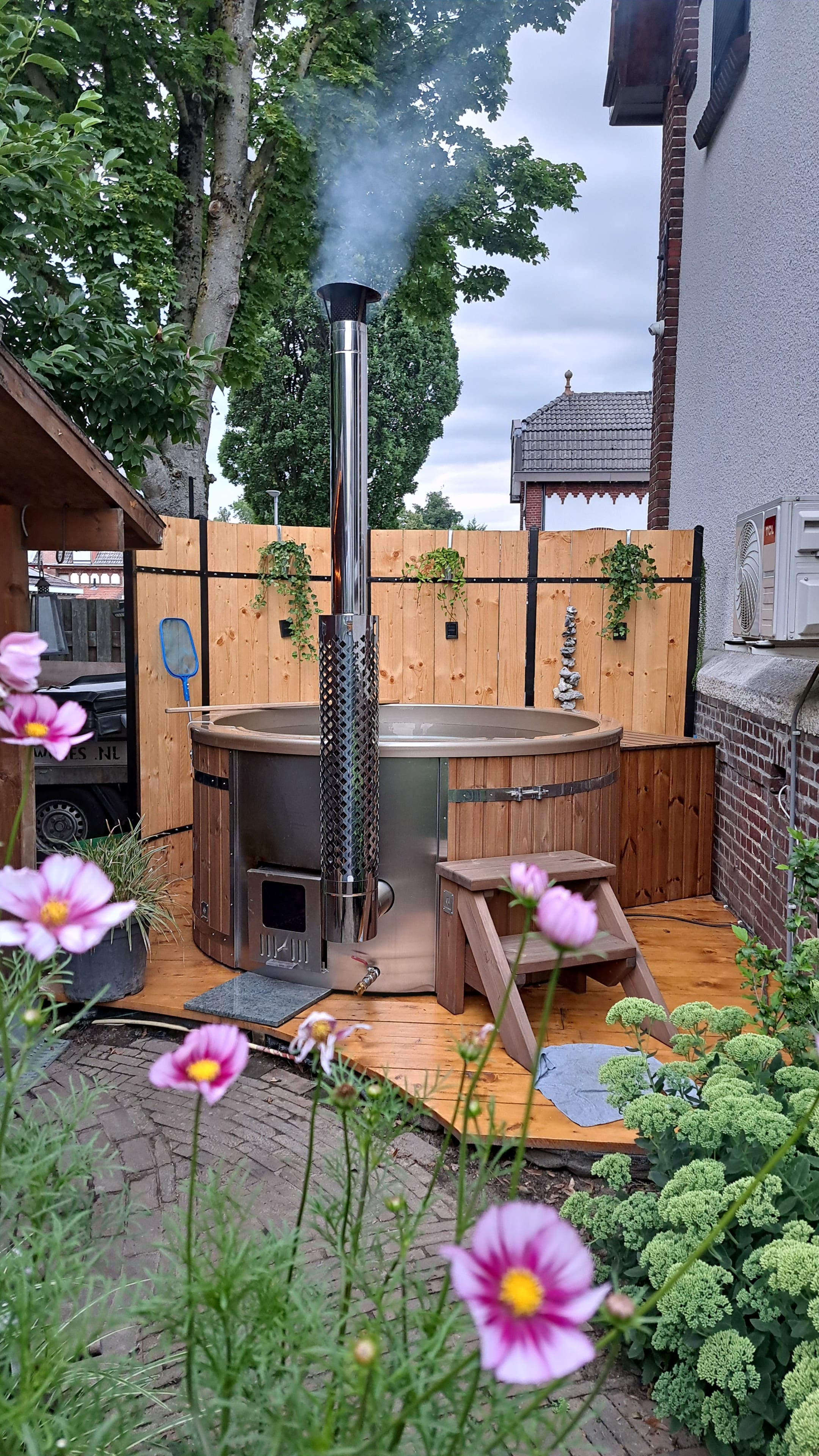 Gardenvity wood fired hot tub in a cozy courtyard garden with flowers and privacy fence.