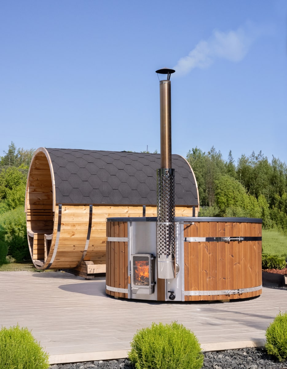 Außenansicht eines hölzernen Hot Tubx mit externem Holzofen und Fasssauna im Garten bei klarem Himmel