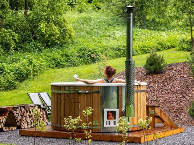 Eine Frau entspannt sich in einer holzbefeuerten Hottub von Gardenvity